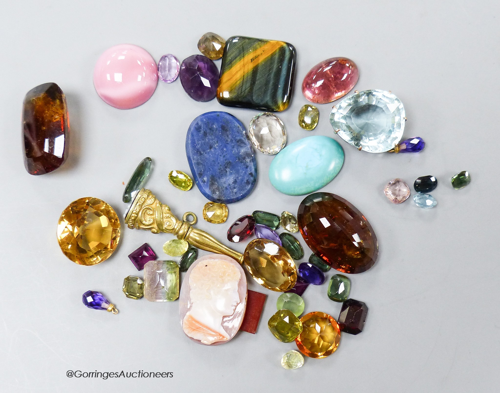 A small collection of unmounted mixed gemstones including citrine and amethyst and an intaglio carving.